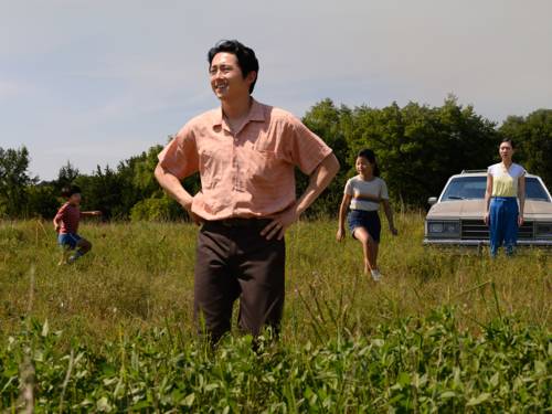 Ein asiatischer Mann steht auf einer Wiese – die Hände in die Hüften gestützt schaut er über das Land. Weiter hinter ihm seine Kinder.